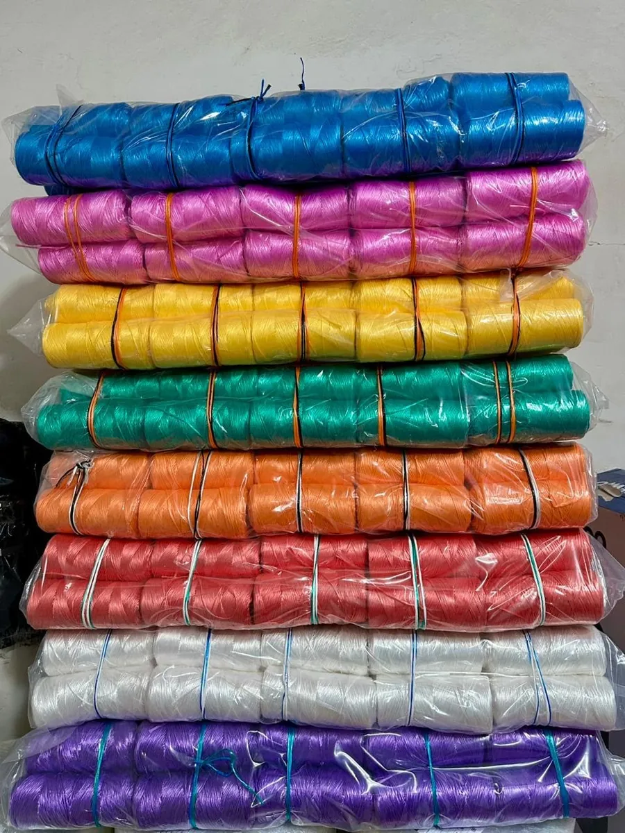 Bultos de rafia para tutoreo apilados en azul, rosa, amarillo, verde y blanco